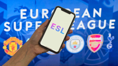 Person holding a phone in front of European Super League banner